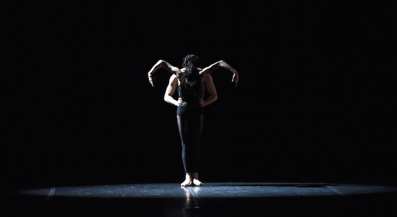 Alessandra Ferri stands with her elbows raised above her shoulders and her head tucked. Cornejo stands directly behind her.